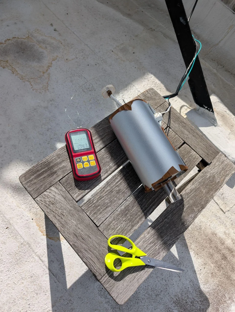 The assembled tube furnace outdoors beside a temperature meter