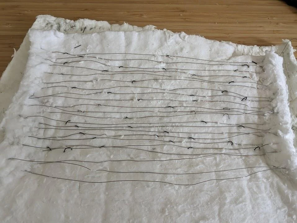 An earlier furnace heating element secured in a switchback pattern on ceramic fiber insulation