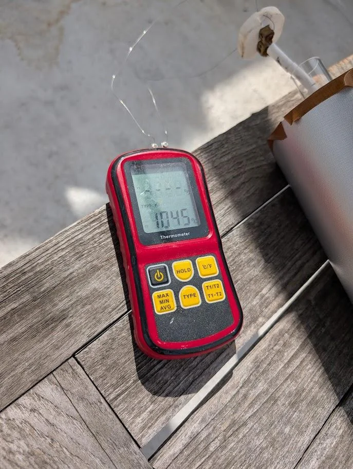 A handheld thermocouple meter monitoring the furnace temperature